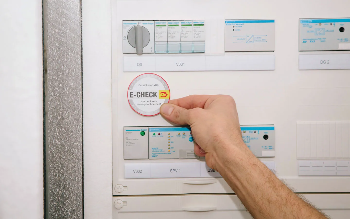 E-CHECK - Mitarbeiter klebt in der Verteilung die E-CHECK Plakette an &middot; Palzer Elektro