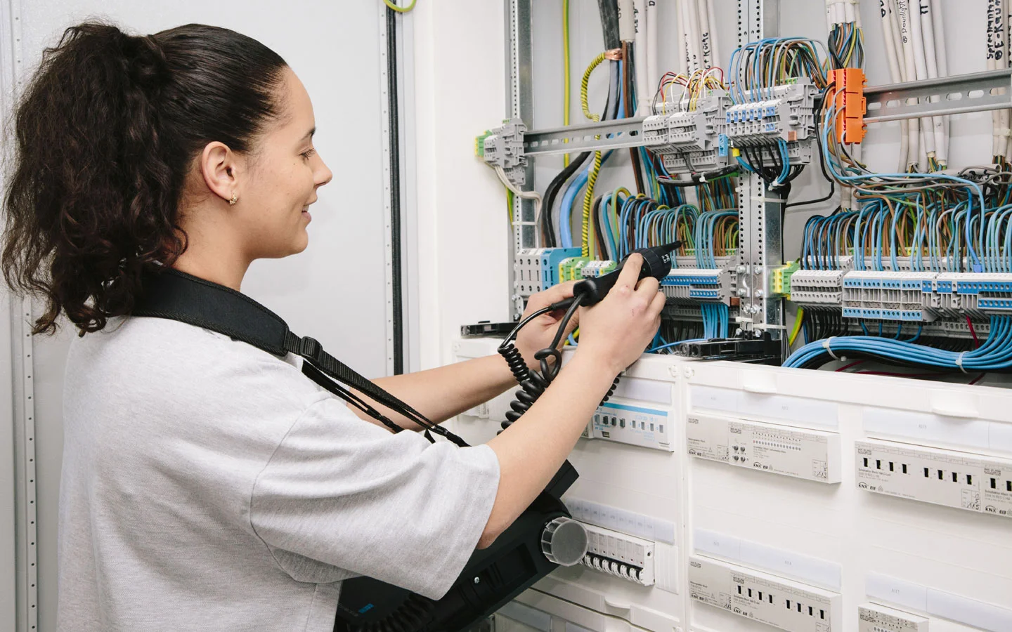 E-CHECK - Mitarbeiterin prüft im Schaltschrank mit einem Meßgerät &middot; Palzer Elektro